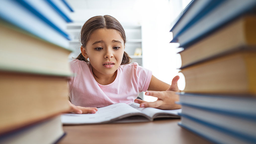a girl who looks stressed out seen between two stacks of books