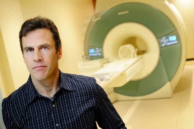 a photo of a man standing in front of a fMRI machine