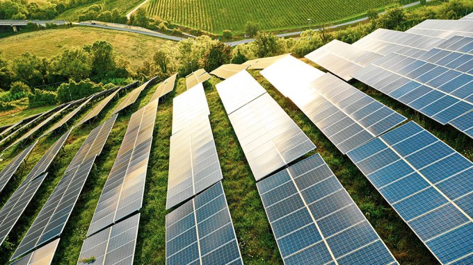 a photo of solar panels on a green hill
