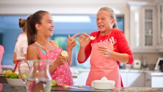 a girl eating a lemon and making an awful face and her friend laughing