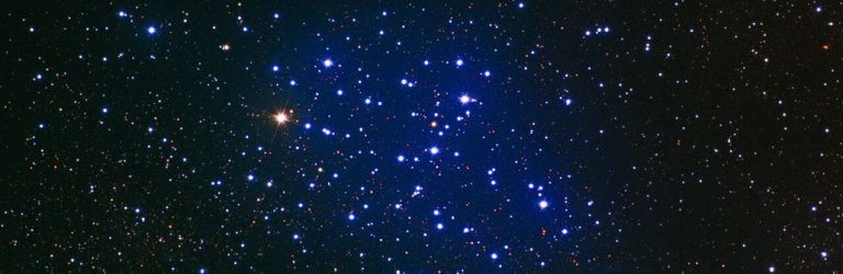 telescope image of a star cluster, which is surrounded by a blue haze