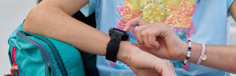 a close up photo of a teen checking her smartwatch, only her torso and arms are in the picture