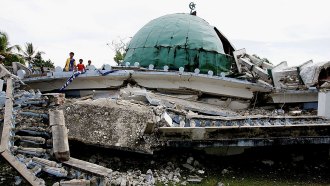 a mosque destroyed after an earthquake, several kids stand to the left