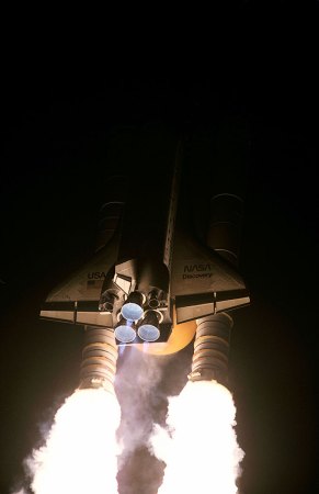 a photo of a nighttime launch of the space shuttle Discovery. The back of the shuttle is lit up by the exhaust from the rockets