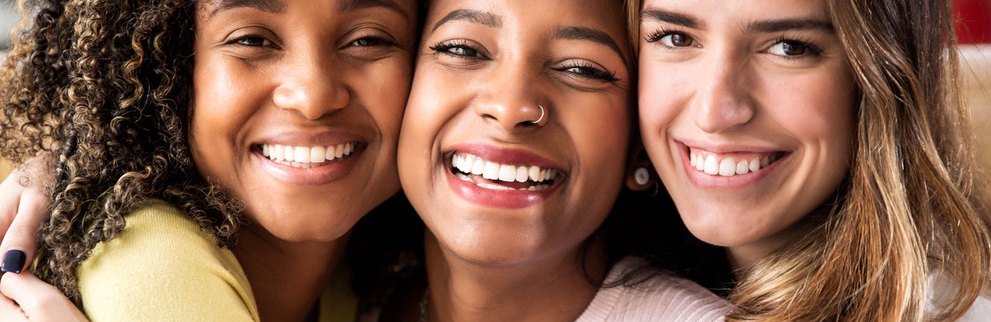 three smiling women pose cheek to cheek