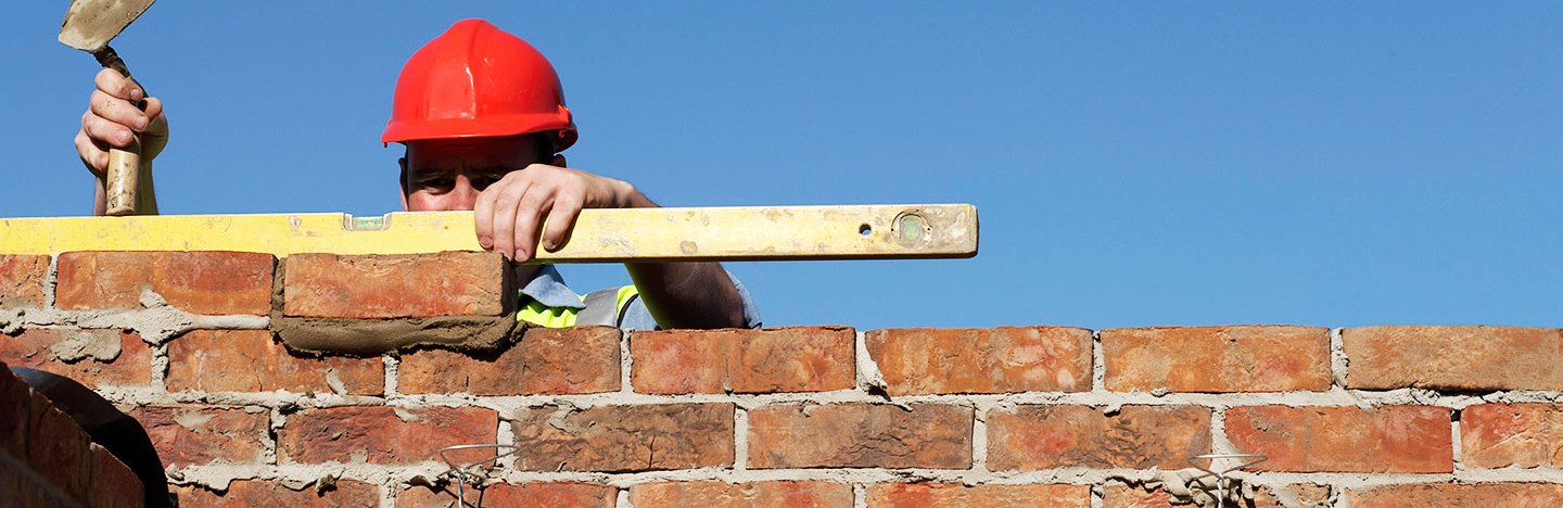 a photo of a brick layer checking to make sure the bricks are level