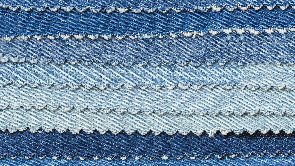 several pieces of denim dyed different shades of blue are fanned out on top of each other