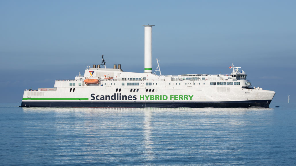 a ferry boat with a tall spinning cylinder in the middle of the boat