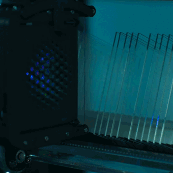 a robotic grip retrieves glass sheets from a rack