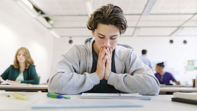 a photo of a stressed out looking high school student staring at a notebook in class