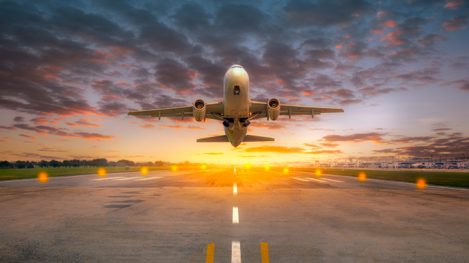 Airplane taking off from the airport runway in beautiful sunset light