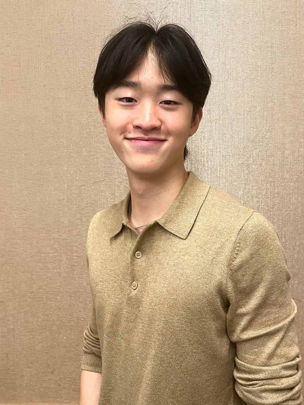 a photo of a smiling young Asian teen wearing a gold shirt