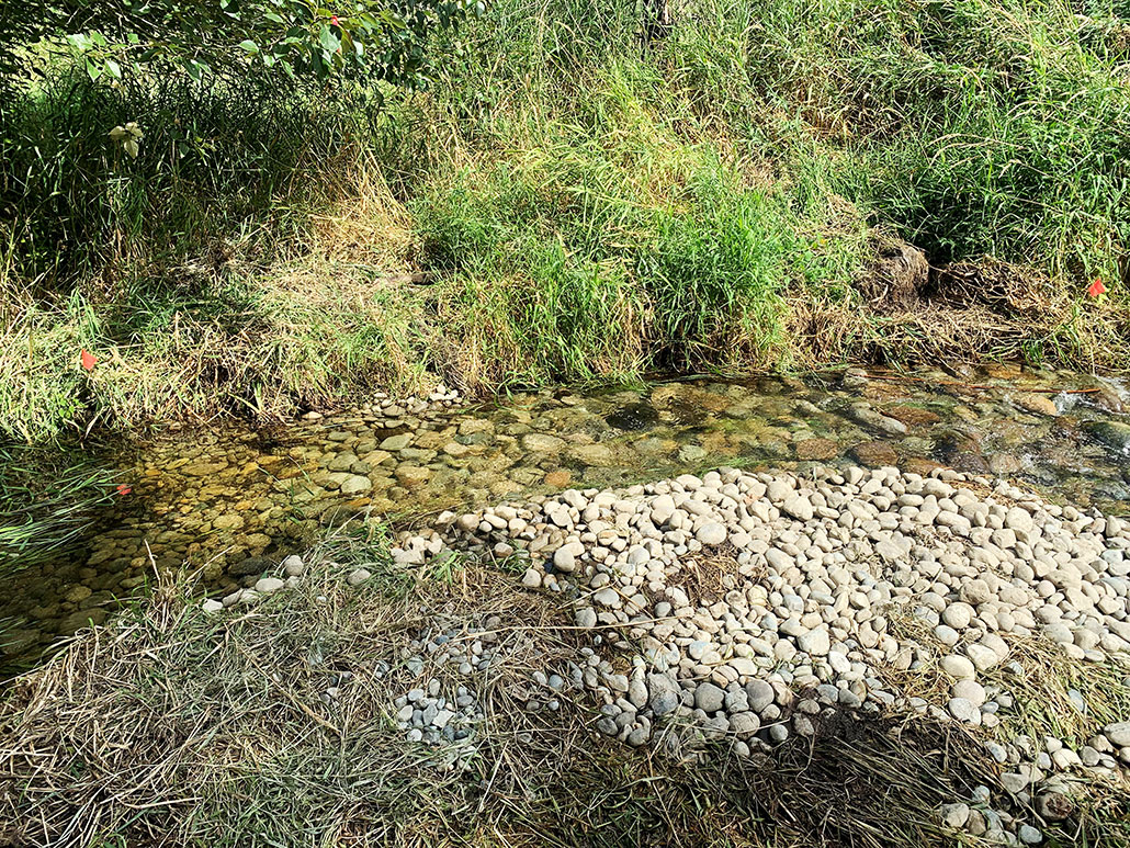 part of a creek after habitat restoration, there are noticeably more rocks in the water