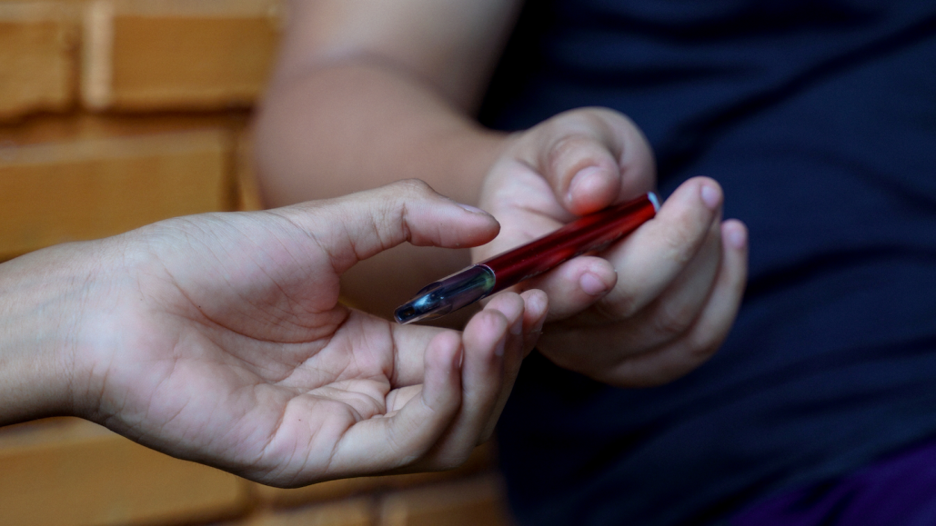 one teen boy hands a vape pen to another teen boy
