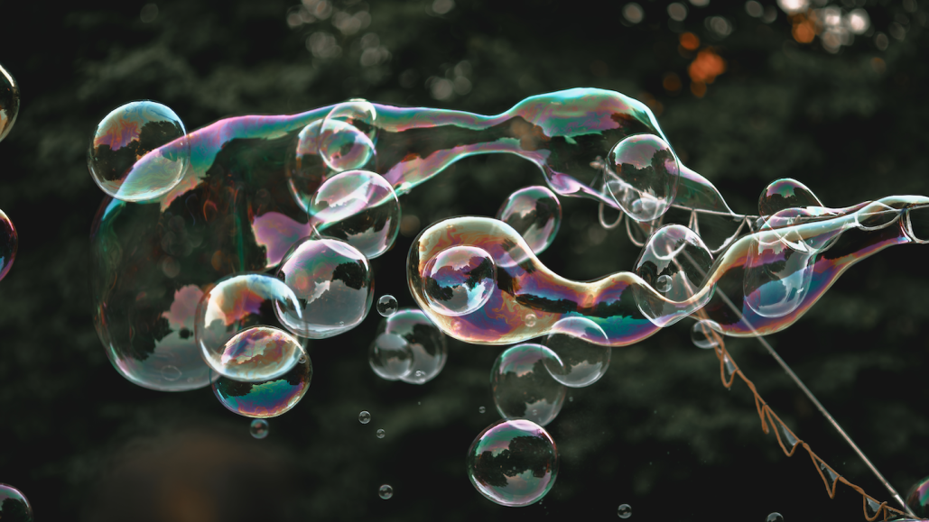 bubbles drift through the wind with trees in the background