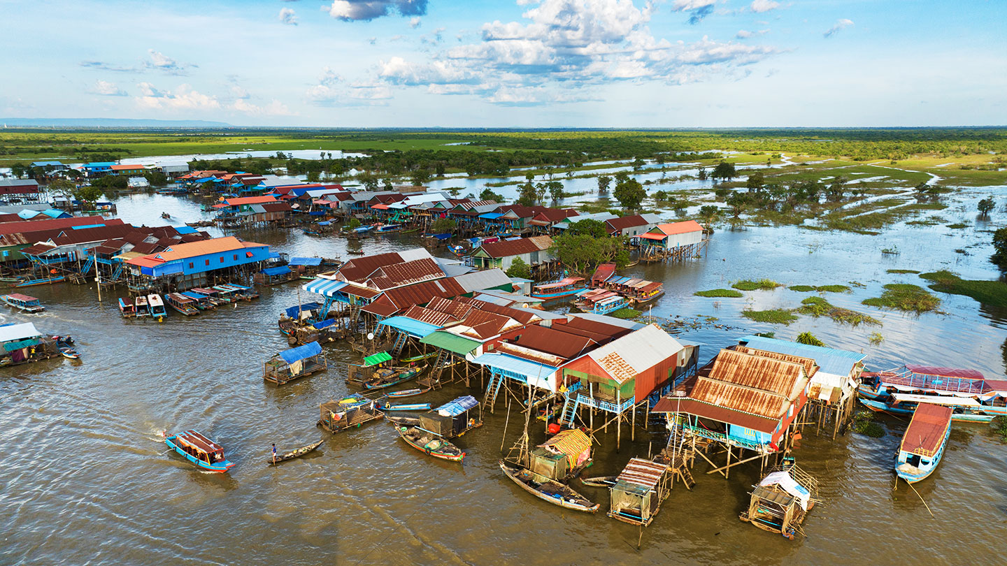 an aerial view of a fishing village on Cambodia's Tonie Sap Lake, houses and shops are on stilts and people use boats to go from structure to structure