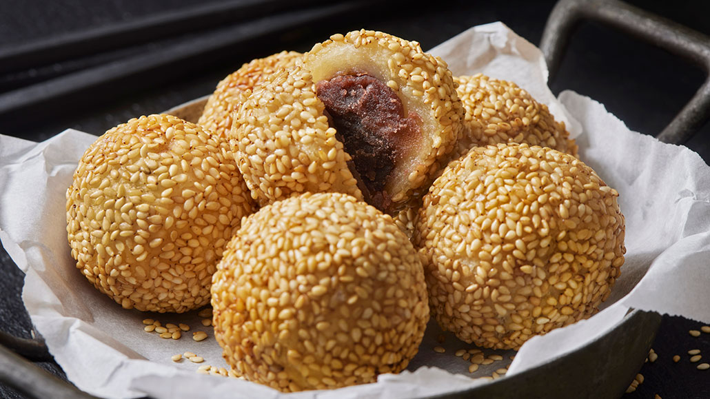 a plate of sesame balls, rice balls fried and coated in sesame seeds filled with red bean paste