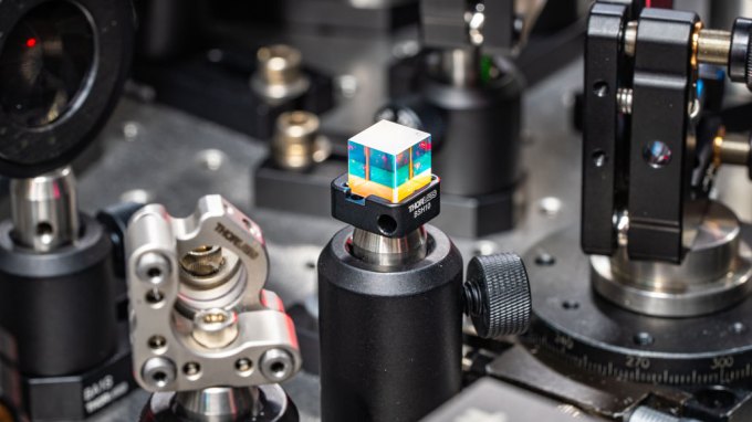 a photo of a laser beam splitter, a small colorful cube, surrounded by laser equipment