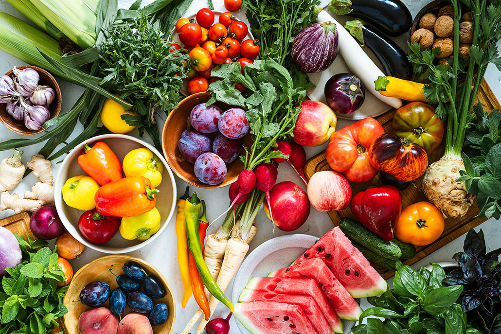 an array of vitamin-rich fruits and vegetbales in every color spread out on a table