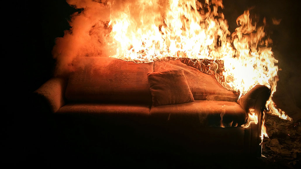 a photo of a couch on fire in a dark room