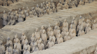 rows of terra cotta soldiers stand guard around a tomb