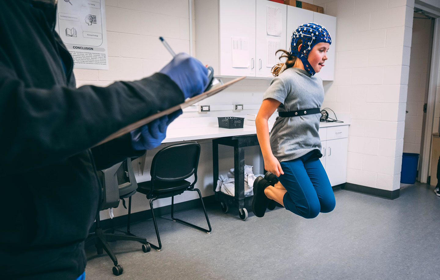 a girl doing jumping exercises and wearing an EEG cap