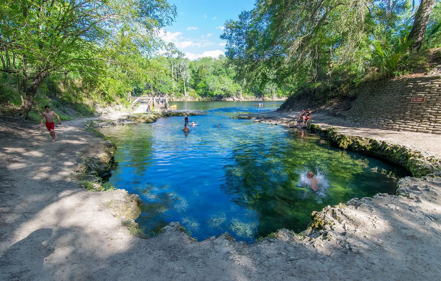 a photo of a sinkhole in Florida filled with water; people are swimming in it