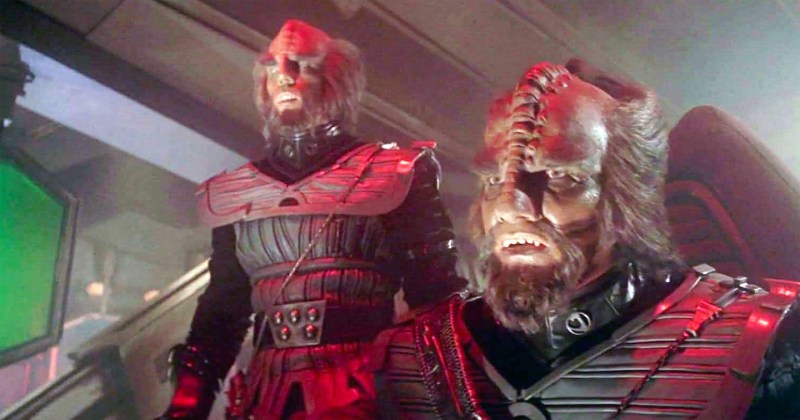 two klingons, humanoid aliens with large ridges on their foreheads and wearing armor, stare open-mouthed at something out of frame
