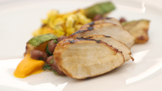 a plate holds a meal of lab-grown chicken with vegetables