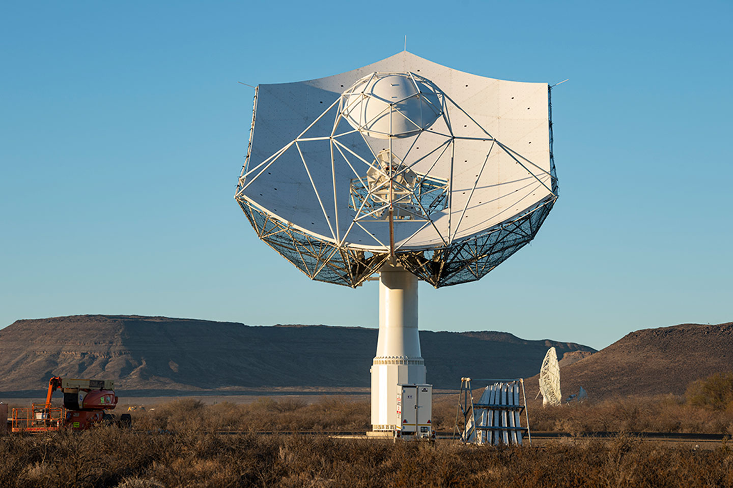 a large radio telescope points at a clear blue sky