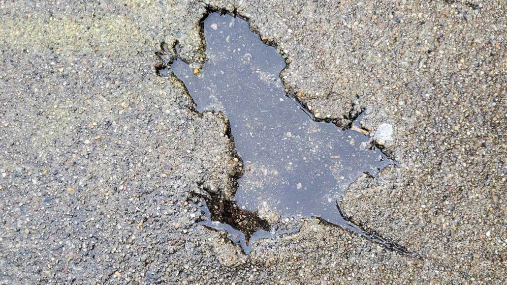 Water fills the crime scene-like outline of Chicago's Rat Hole, a rodent-shaped crater in concrete with visible foot, toe and tail impressions.
