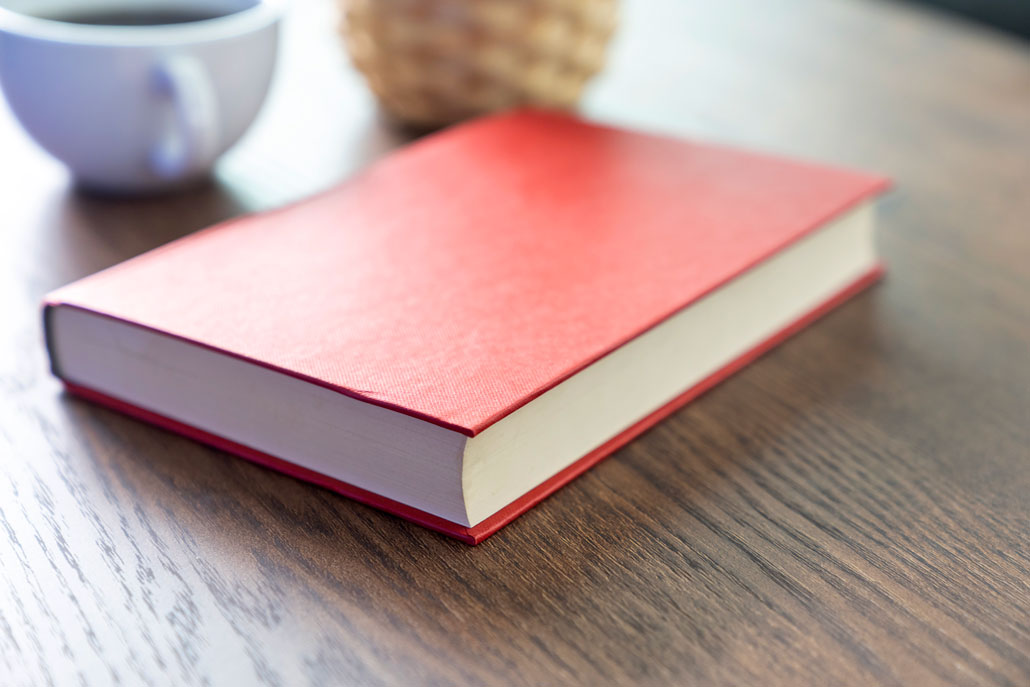 a red hardback book on a wood table