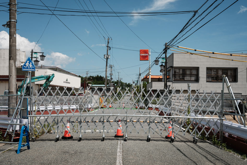 a folding fence across a road prevents people and vehicles from entering the Fukushima exclusion zone