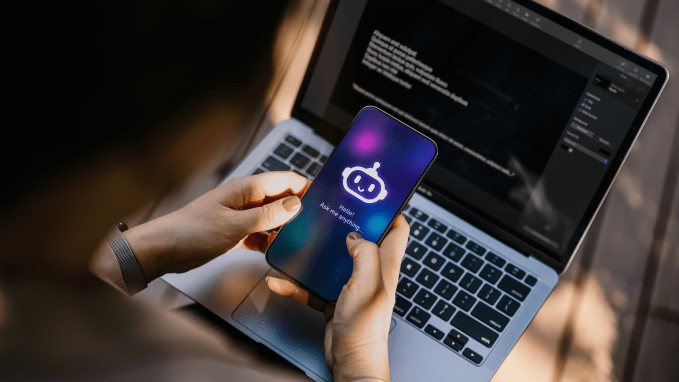 a person holds up a phone with a chatbot icon on the screen, and the chatbot saying 'hello! ask me anything'