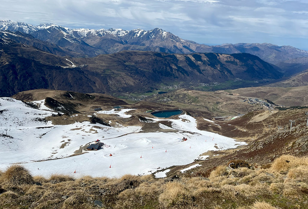 A photo looking down a mountain at a ski course, there is machine made snow on the course, but nowhere elseIn warm or dry winters, many ski competitions take place on artificial snow, such as here at Val-Louron, a ski resort in the French Pyrenees, in March 2023. It was an unusually warm month worldwide.