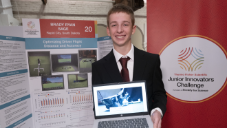 a teen boy smiles as he stands in front of a scientific poster titled "Optimizing Driver Flight Distance and Accuracy"