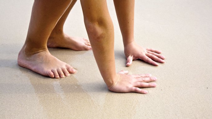 a photo of a child's hands and feet on a sandy beach, to demonstrate the idea of chirality