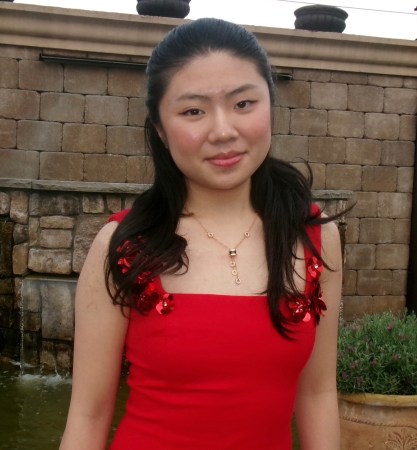 A teen girl in a red dress smiles at the camera