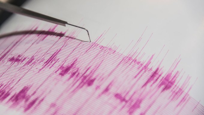 a seismograph scribbles out earthquake data in pink pen