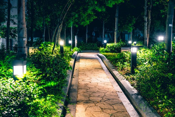 a garden path at night, with lanterns on either side light the path