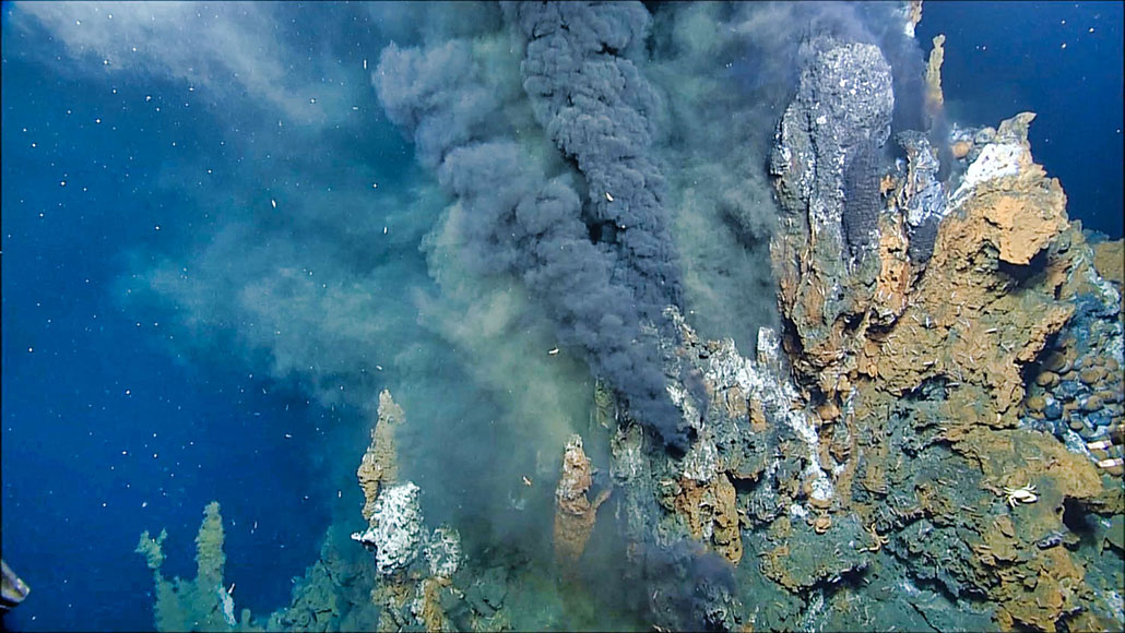 an underwater photo of a hydrothermal vent spewing black 'smoke' into the surrounding water