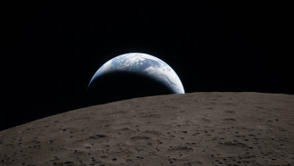 an Artemis II mission photo of the Earth seen rising over the surface of the moon