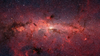 the band of the Milky Way galaxy shown in red light stretches across the sky