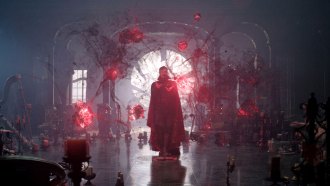 a still from Doctor Strange in the Multiverse of Madness, showing a cloaked figure silhouetted against a round window and surrounded by glowing orange balls of material