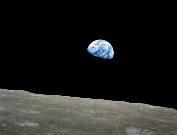 Earth rises beyond the horizon of the lunar surface