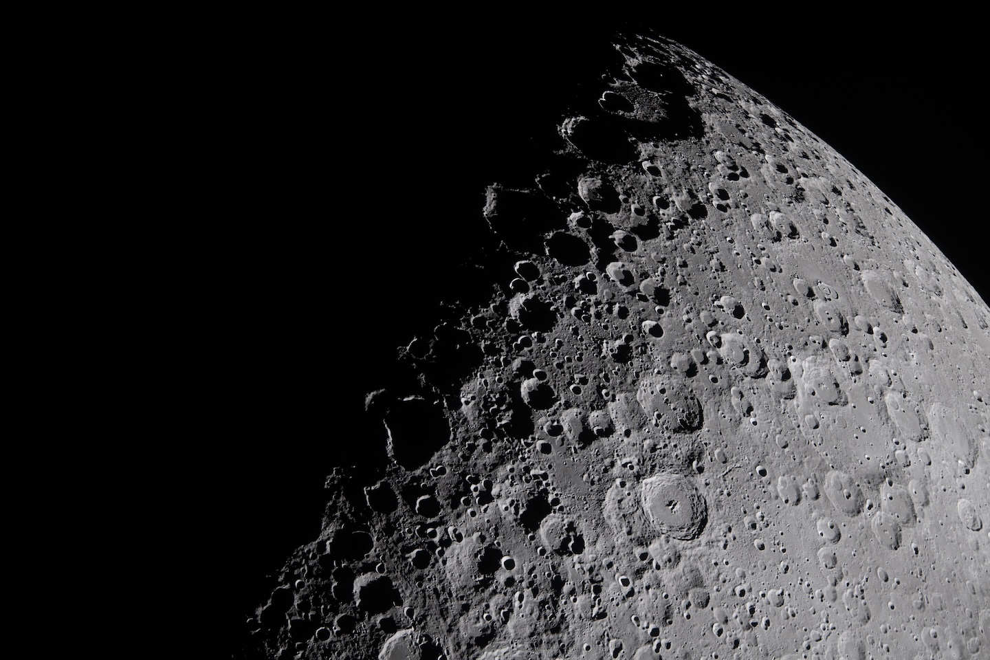 a close up view of the moon shows the shadows of its pockmarked surface