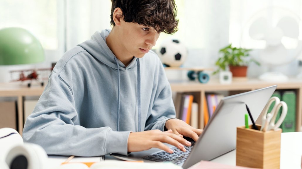 a teen boy is working on a laptop