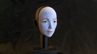 a photo of a humanoid robot face on a rod against a black backdrop