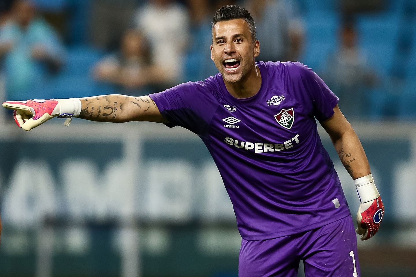 a man in a purple soccer jersey yells and points to the left of the picture