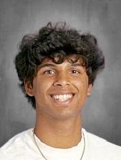 a headshot of a smiling teen with curly black hair and brown skin